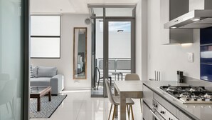 Una cocina moderna con estufa a gas, un comedor con mesa y sillas, y una sala de estar con sofá y mesa de centro.