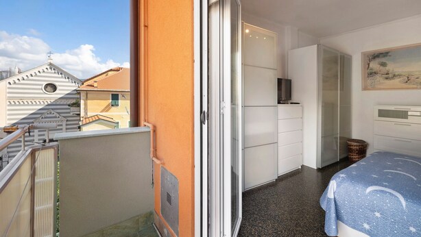 A bedroom with a bed, a wardrobe, and a sliding glass door leading to a balcony. - Apartment "A due passi dal mare" with Mountain View, Balcony & Wi-Fi (Pietra Ligure)
