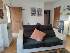 A modern living room with a sofa, a cabinet, and a door.