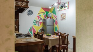 Una cucina con un orologio, un frigorifero e un tavolo da pranzo con sedie.