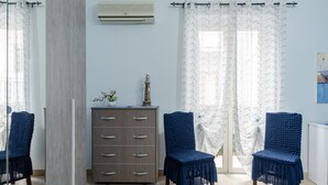 Una stanza con due sedie blu, un armadio in legno e una finestra con tende a motivi.