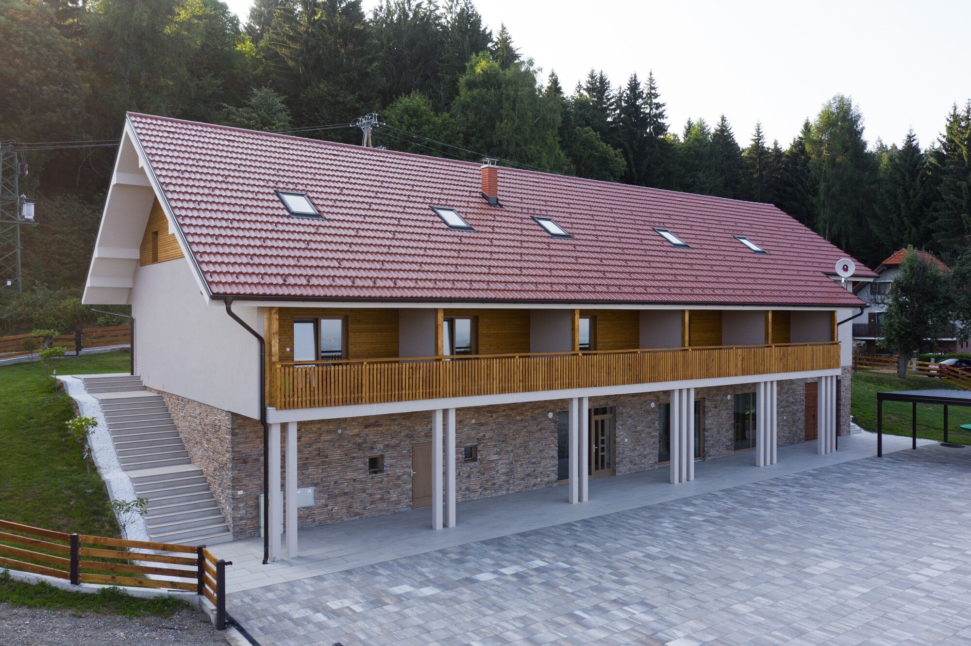 A two-story building with a red-tiled roof, a balcony, and stone walls.