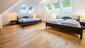 Une chambre avec deux lits, des fenêtres de toit, un plancher en bois et des lampes de chevet.