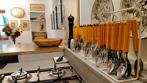 A kitchen with a gas stove, a utensil rack with yellow handles, and a decorative plate on the wall. - Holiday Home 'Casa Annamaria' (Arcola)