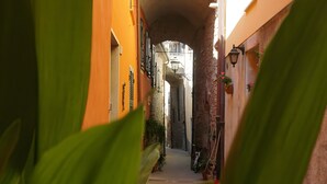 A narrow alleyway with a stone archway, flanked by buildings with balconies and potted plants. - Holiday Home 'Casa Annamaria' (Arcola)