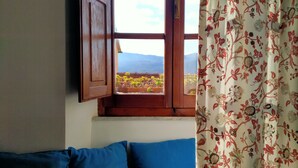A room with a window, a blue sofa, and a curtain with a floral pattern. - Holiday Home 'Casa Annamaria' (Arcola)