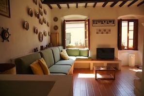Een gezellige woonkamer met een bank, televisie en diverse decoratieve objecten aan de wanden.