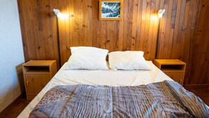 A wooden-paneled room with a bed, two bedside tables, and a framed picture on the wall.