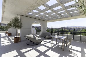 A rooftop terrace with a modern design, featuring a seating area with a sofa and chairs, a small table, and potted plants. - Líbere Pamplona Yamaguchi (Pamplona)
