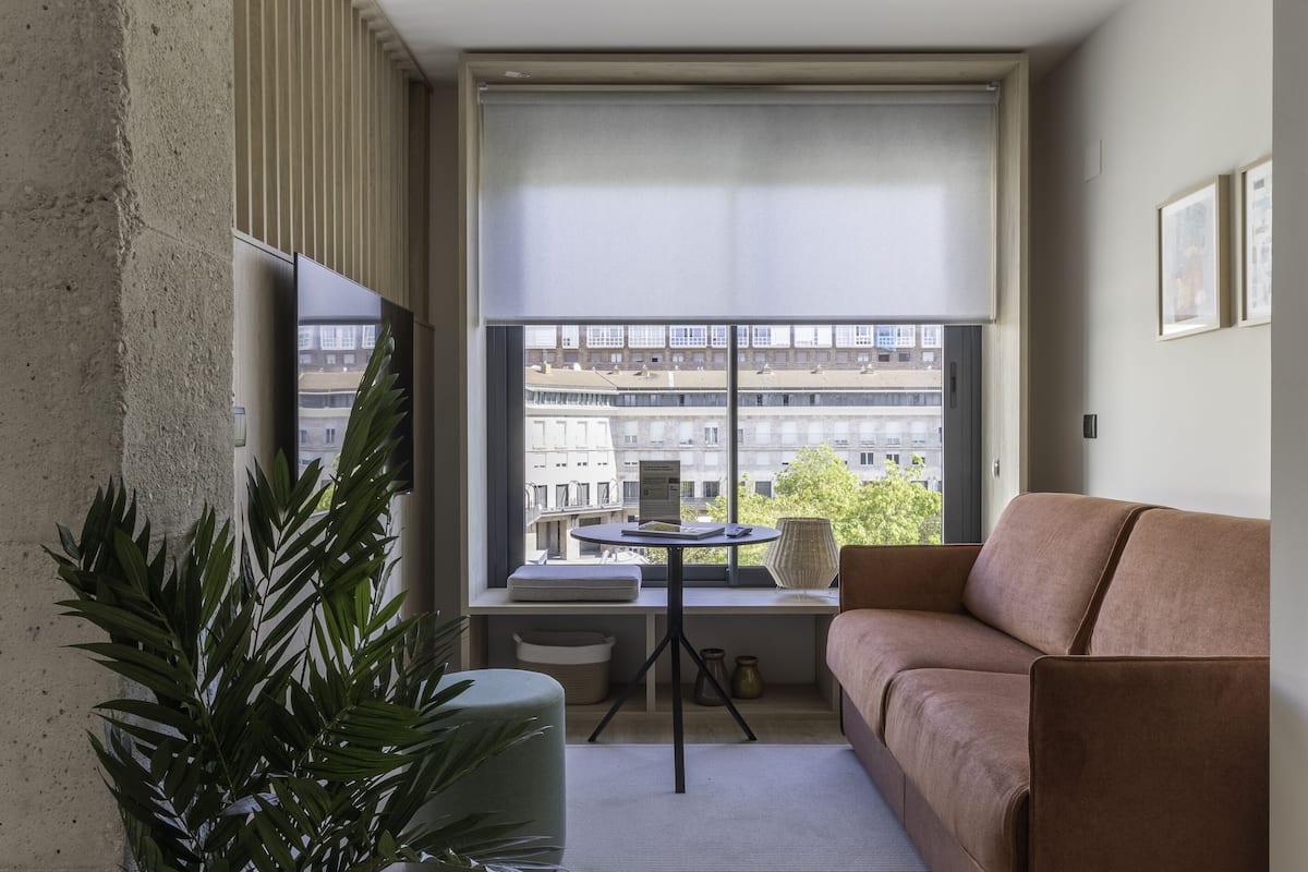 A modern living room with a sofa, a small table, and a potted plant.