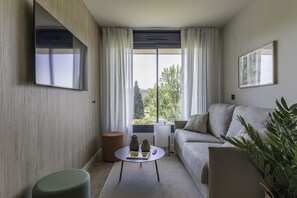 A modern living room with a sofa, a coffee table with decorative items, a television mounted on the wall, and a large window with curtains. - Líbere Pamplona Yamaguchi (Pamplona)