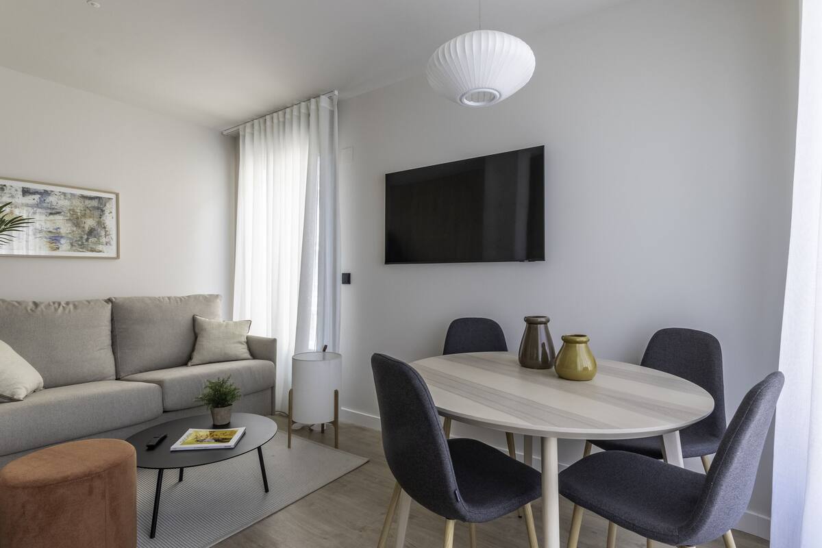 A modern living room with a sofa, coffee table, and dining table with chairs.