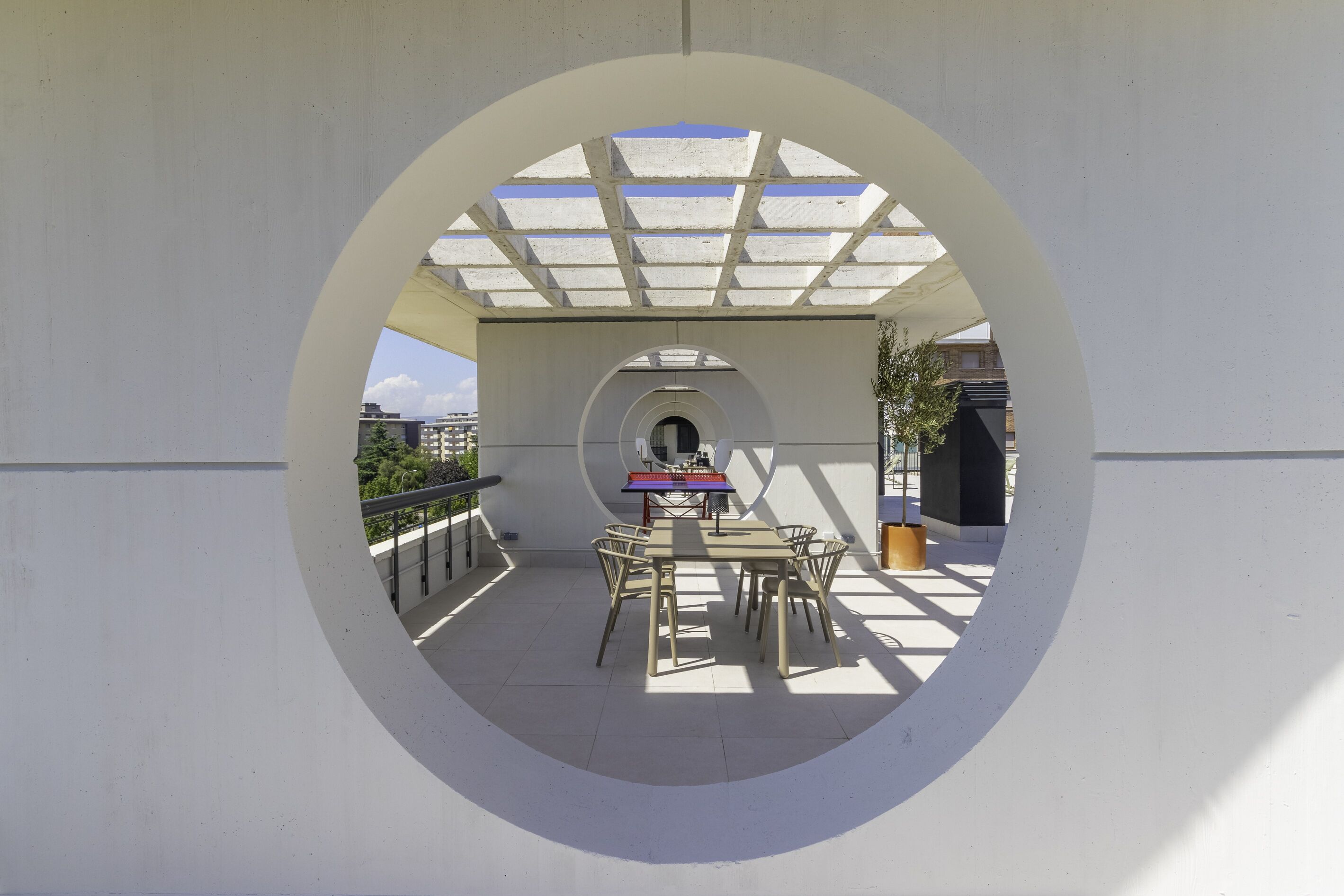 A circular view of a covered outdoor area with a table and chairs, a bench, and a trash bin.