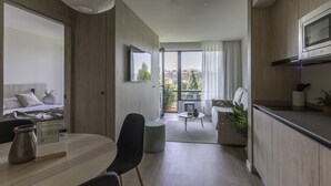 A modern hotel room with a dining area, kitchenette, and a large window offering a city view. - Líbere Pamplona Yamaguchi (Pamplona)
