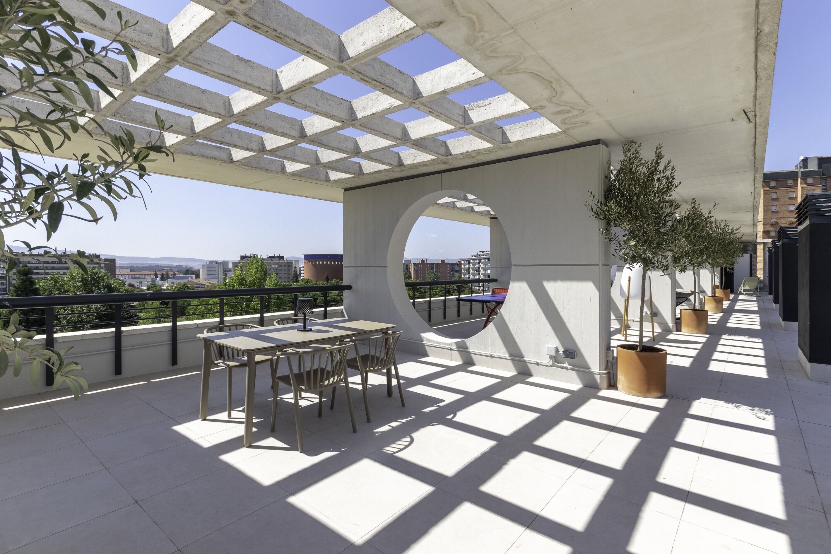 Una terraza al aire libre con una pérgola, zona de estar y plantas en macetas.