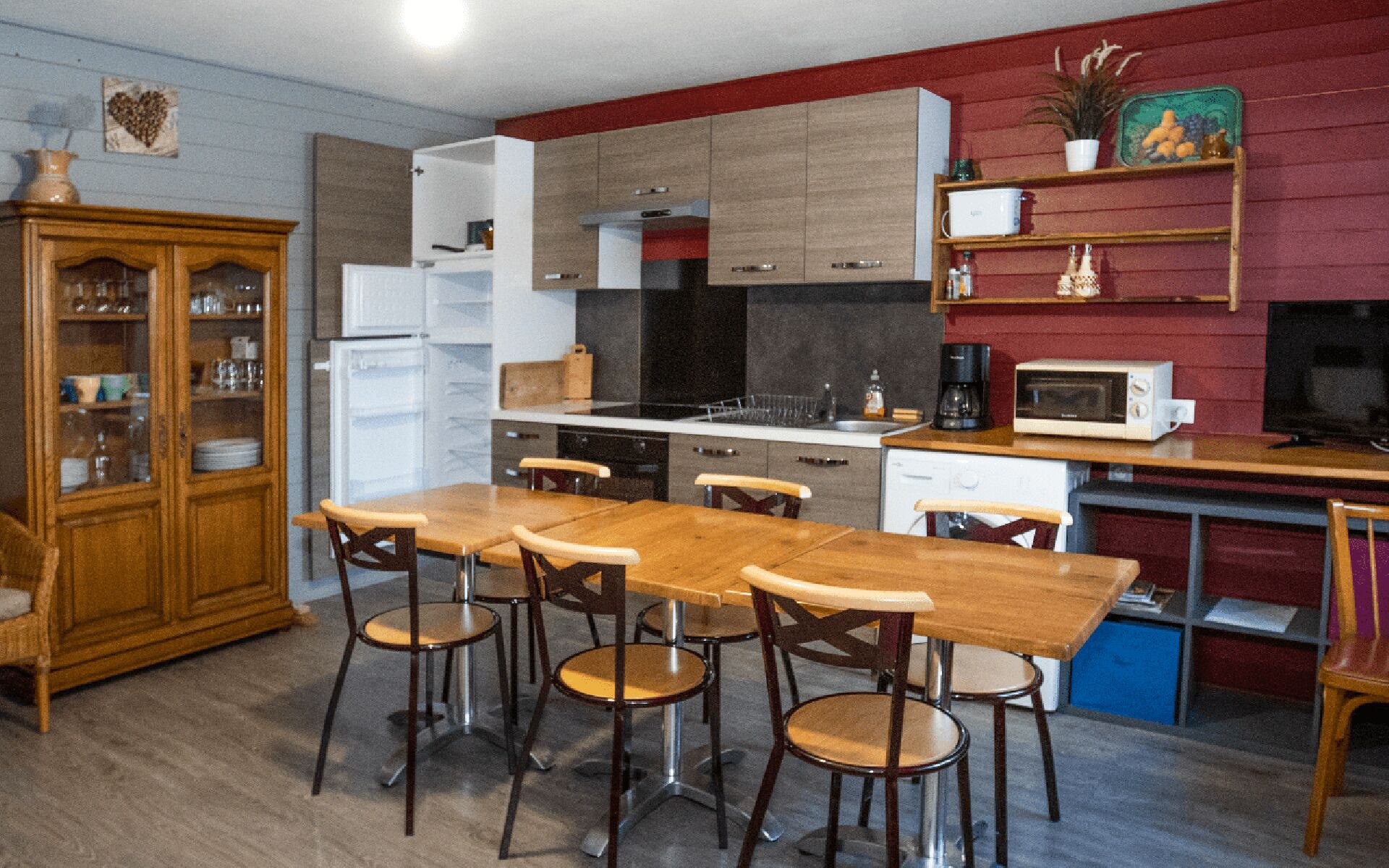 Una cocina compacta con comedor, muebles de madera, refrigerador, microondas y cafetera.