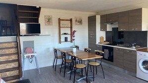 A compact kitchen with a dining area, built-in appliances, and a TV. - Welcome to Genets du Sancy (BESSE-ET-SAINT-ANASTAISE)