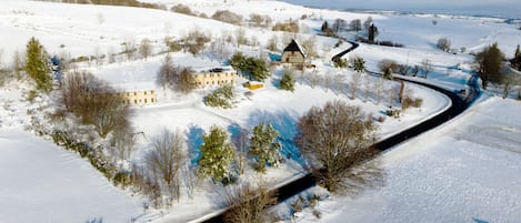 A snow-covered landscape with a road curving through it, surrounded by buildings and trees.