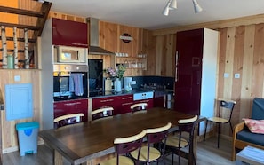 Une cuisine aux murs en bois, une table à manger avec des chaises et un réfrigérateur rouge.