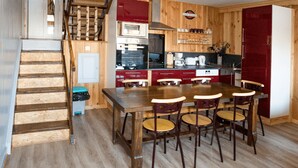 Une cuisine avec une table à manger et des chaises, un escalier et un lambris en bois.