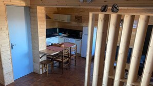 Un intérieur en bois comprenant un coin cuisine, une table à manger avec des chaises et une porte.
