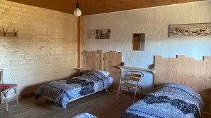 Une chambre avec deux lits, une chaise, un bureau et un luminaire suspendu.