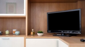 A modern room with a wooden desk, a flat-screen TV, a small potted plant, and a few decorative items. - Pet-Friendly Apartment 'La Colombera' with Sea View, Garden & Wi-Fi (Alassio)