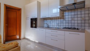 Una cocina con armarios blancos, una estufa y un salpicadero de azulejos.