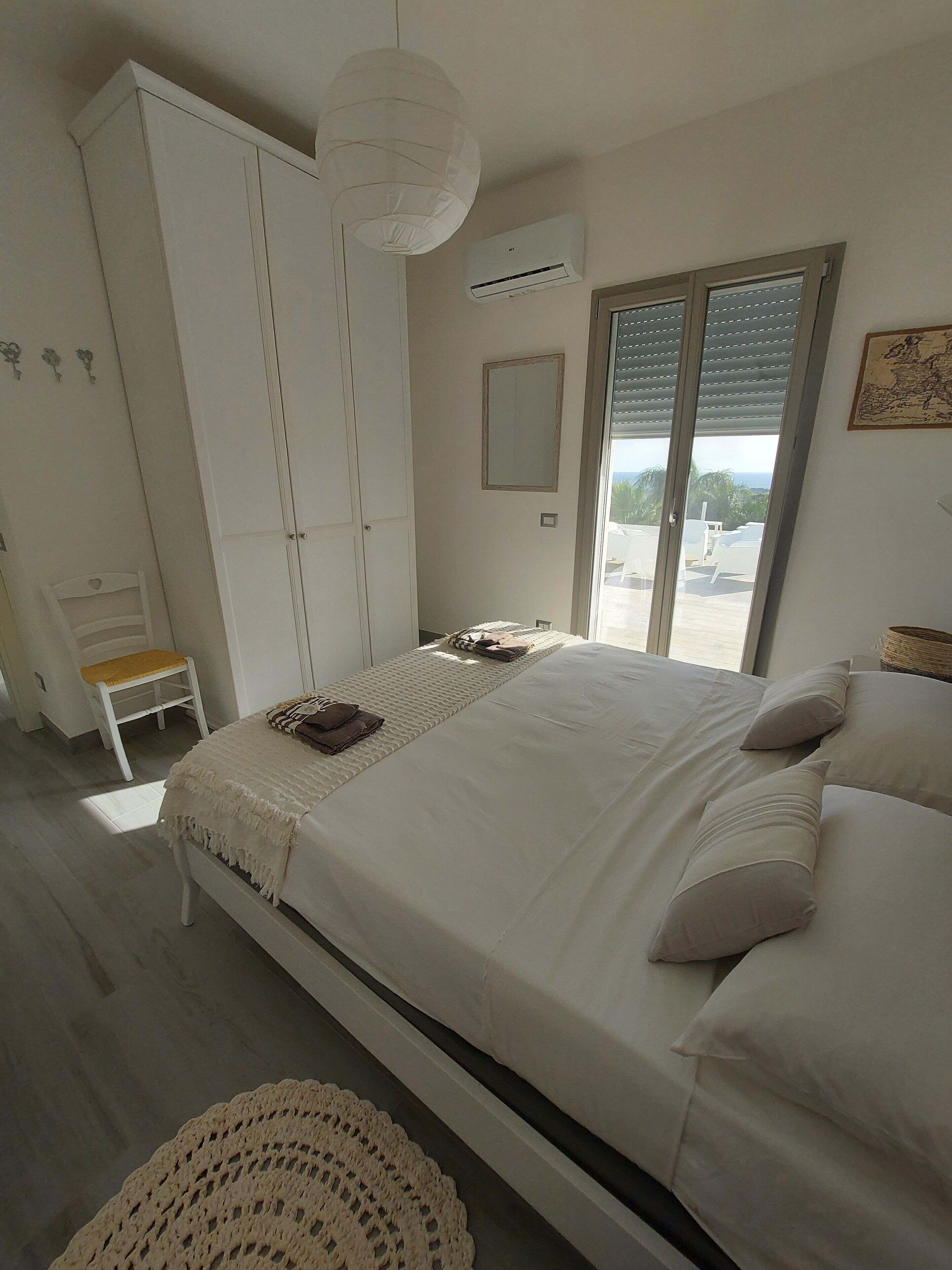 A bedroom with a bed, wardrobe, and a view through a sliding door.