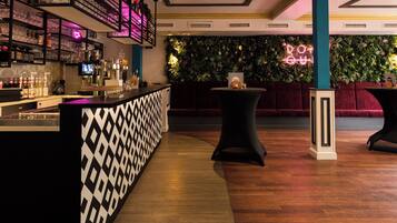 Eine Bar mit Regalen voller Gläser und Flaschen, einem Neonlichtschild und einem Holzboden.