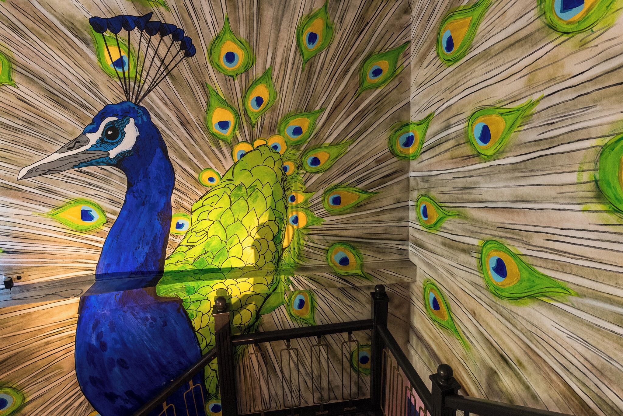 A peacock sculpture with a peacock feather pattern on the wall.