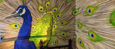 Una escultura de un pavo real con un diseño de pluma de pavo real en la pared.