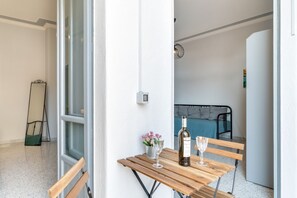 A room with a wooden table, two wine glasses, a bottle of wine, and a small vase with flowers.