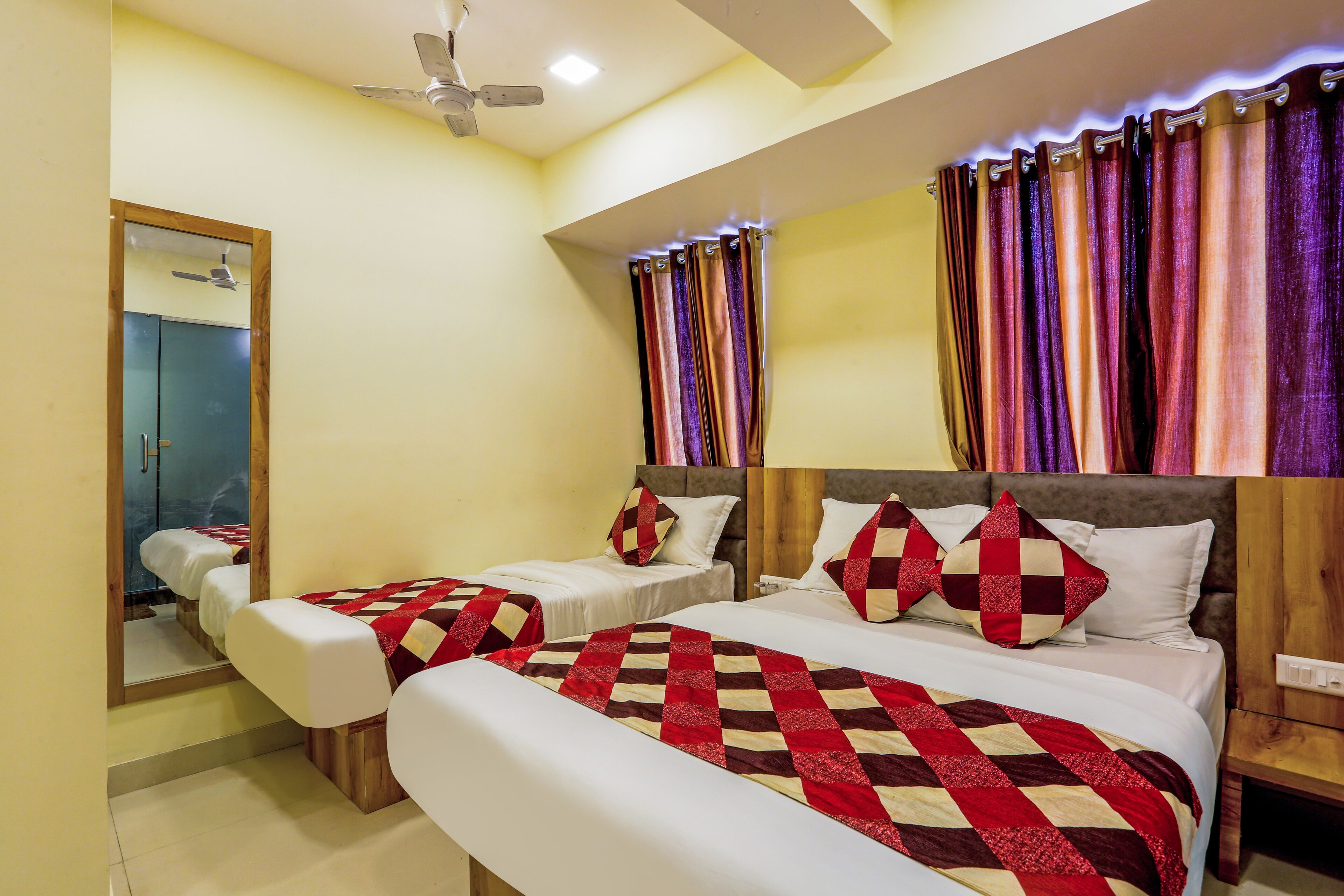 A hotel room with two beds, a ceiling fan, and a mirror.