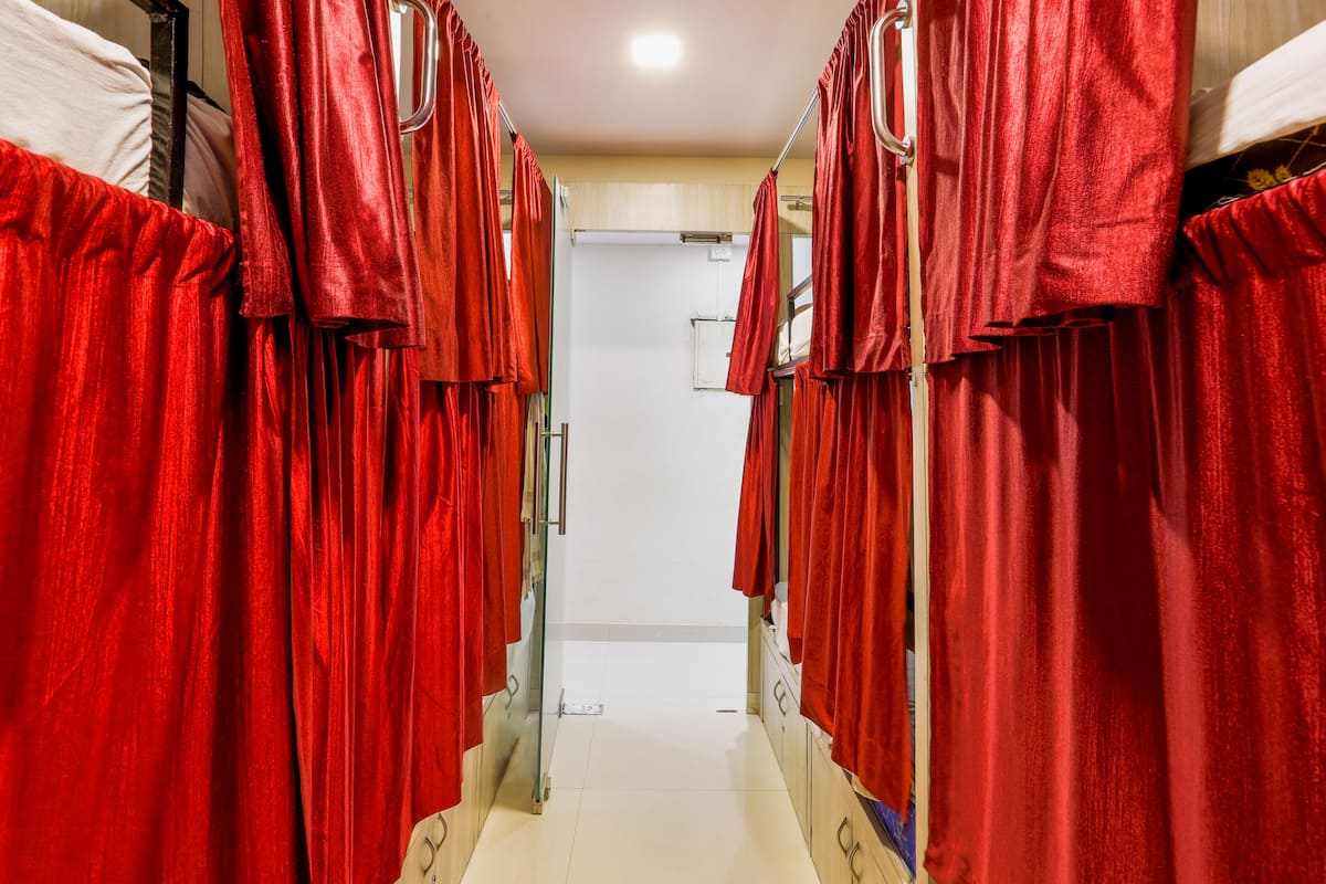 A corridor with red curtains, a white door at the end, and a tiled floor.