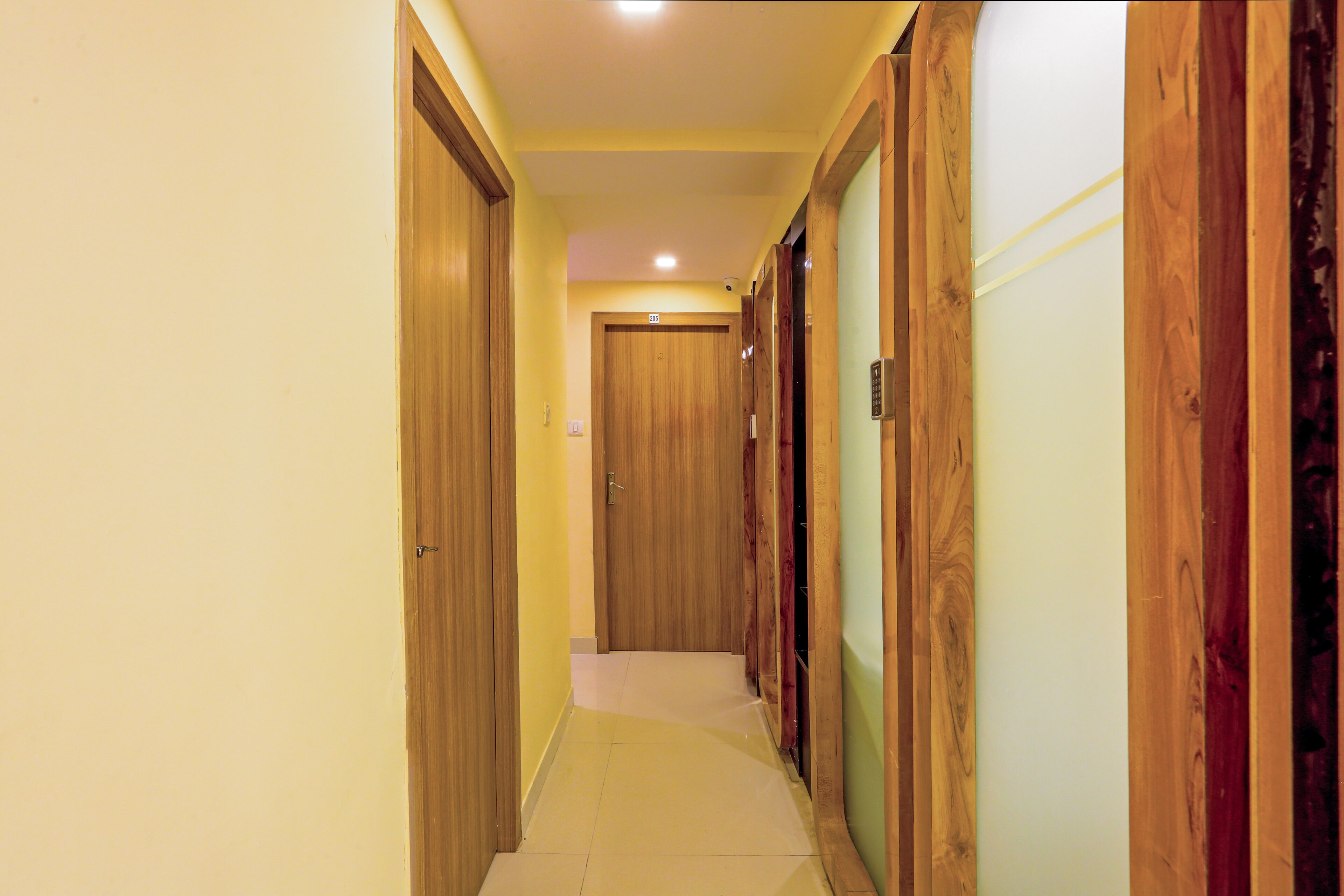 A narrow hallway with wooden doors and a tiled floor.