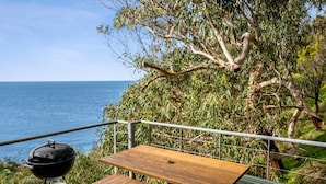 An outdoor deck with a barbecue grill, a table, and a view of the sea. - Hideaway At Wye (Wye River)