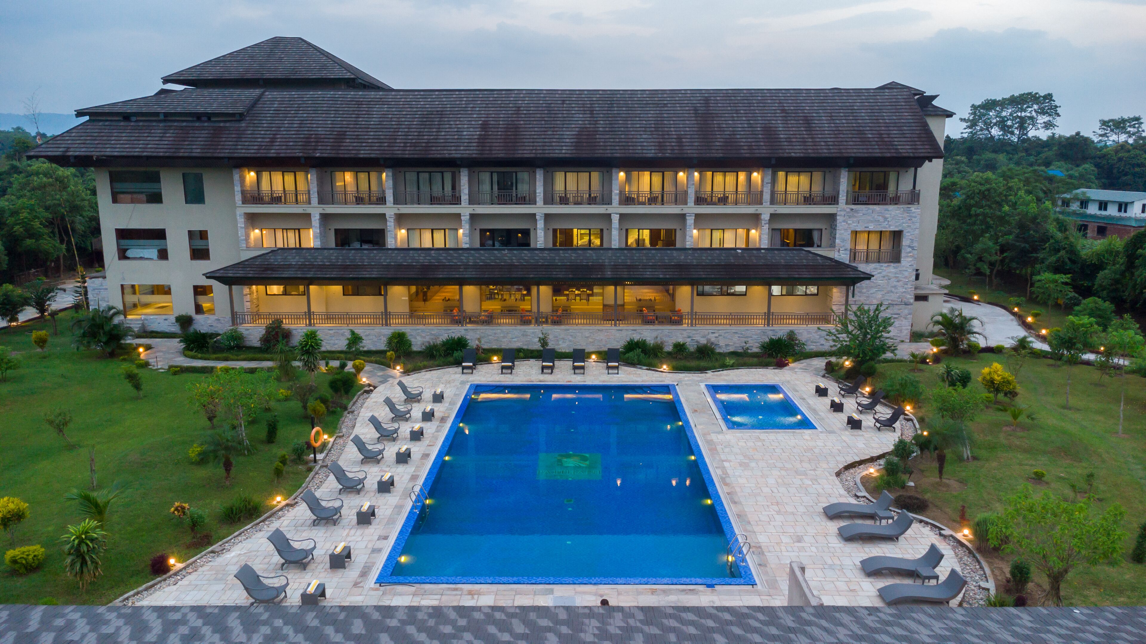 A hotel with a large swimming pool, multiple balconies, and a well-maintained garden.