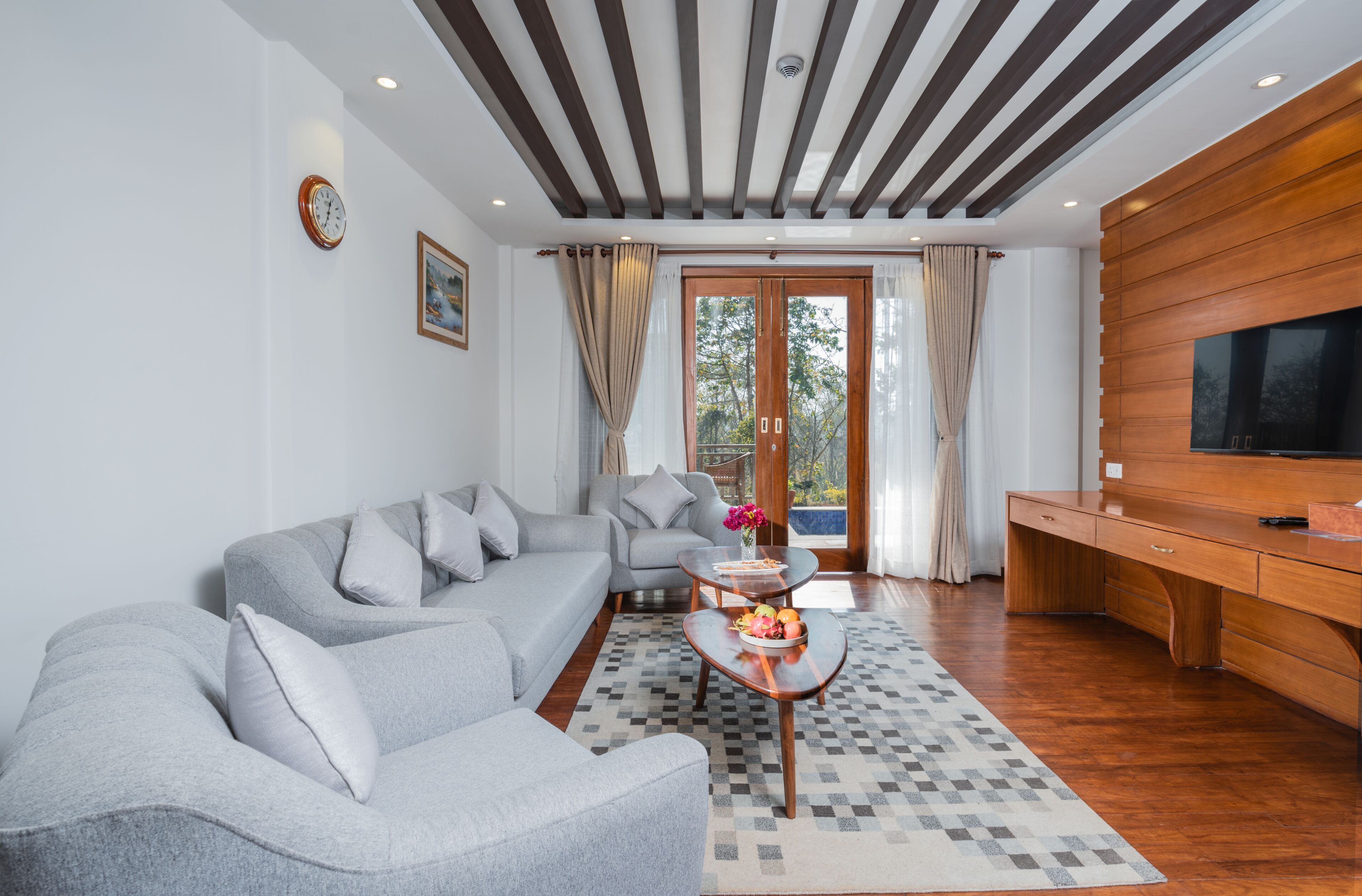 Uma sala de estar moderna com um sofá cinzento, uma mesa de centro com frutas e um móvel de TV em madeira.