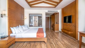 Una habitación de hotel moderna con una cama grande, suelo de madera, un televisor montado en la pared y techo de madera.