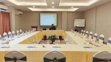A conference room with a long table, chairs, a podium, and a presentation screen.