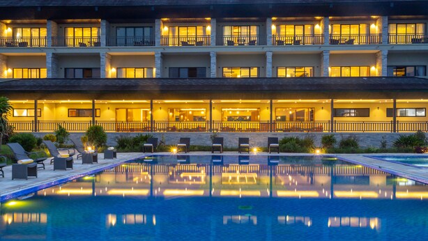 Un hotel con piscina, varios balcones y zonas de estar al aire libre.