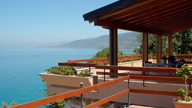 A terrace with a view of the sea, wooden railings, and outdoor seating. - Villa Mytilene II by Wonderful Italy (Cefalù)