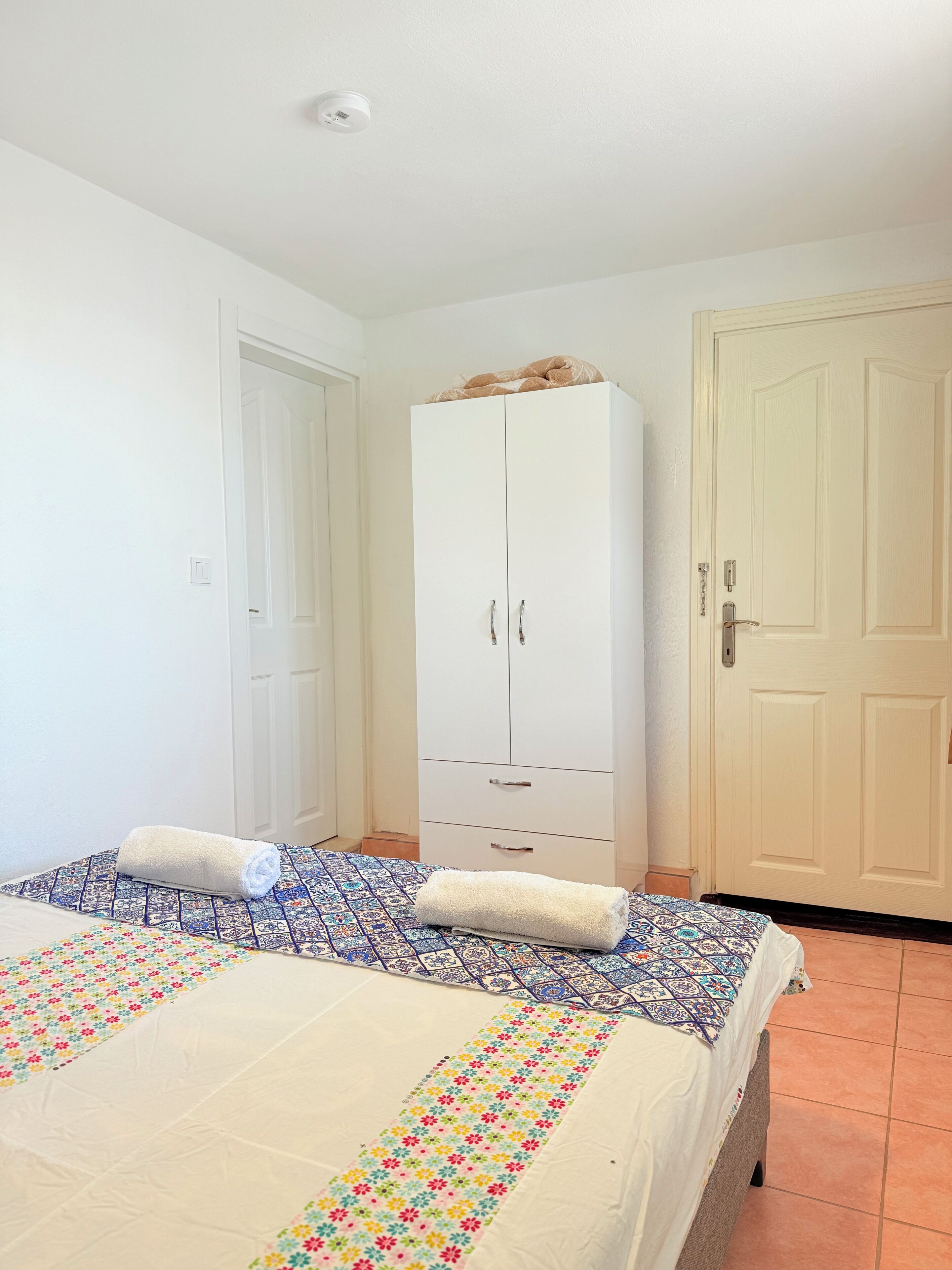 A bedroom with a bed, a wardrobe, and a door.