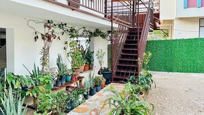 Een gebouw met een trap naar een balkon, omringd door potplanten en een stenen pad.