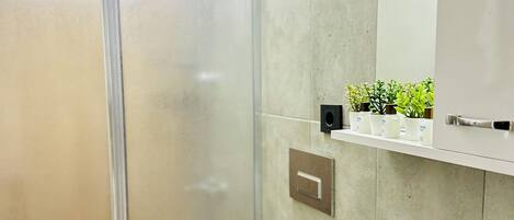 Un baño con ducha de vidrio, inodoro y lavabo con dispensador de jabón azul.