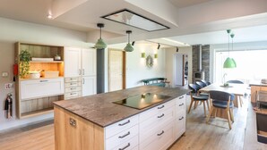 A modern kitchen with a central island, wooden cabinets, and pendant lighting.