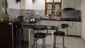Una cocina compacta con refrigerador, pileta, estufa y dos taburetes de bar.
