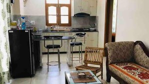 Un espacio habitable compacto con kitchenette, un sofá y una mesa de comedor.