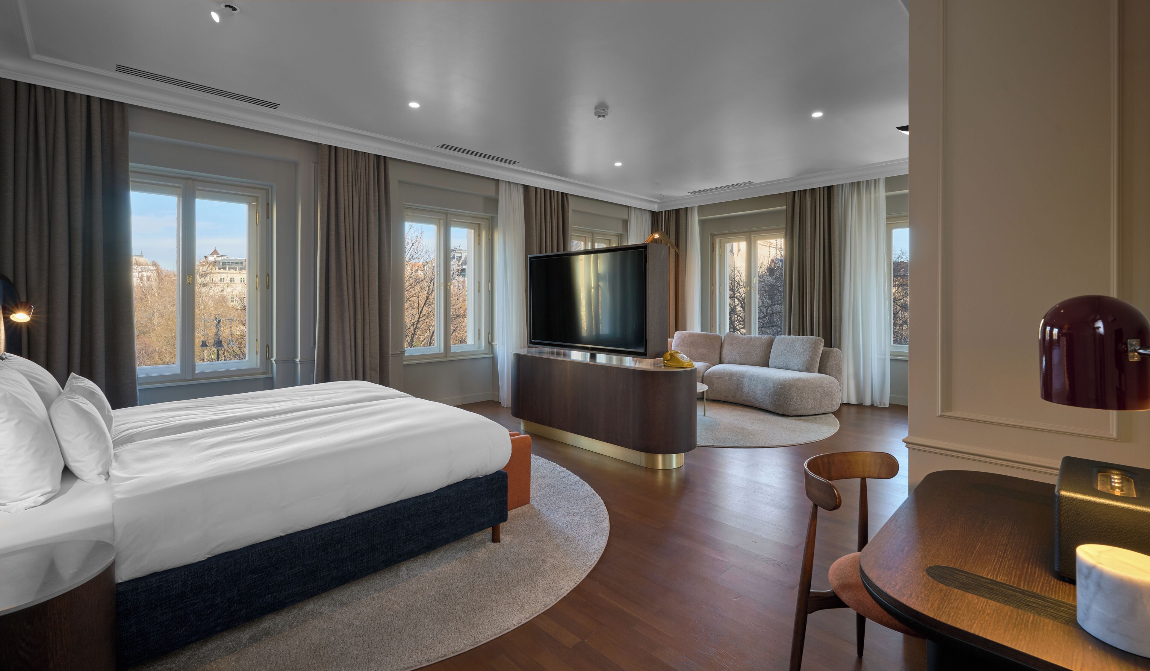 Una habitación de hotel moderna con una cama grande, televisión de pantalla plana, sofá y una mesa de comedor.